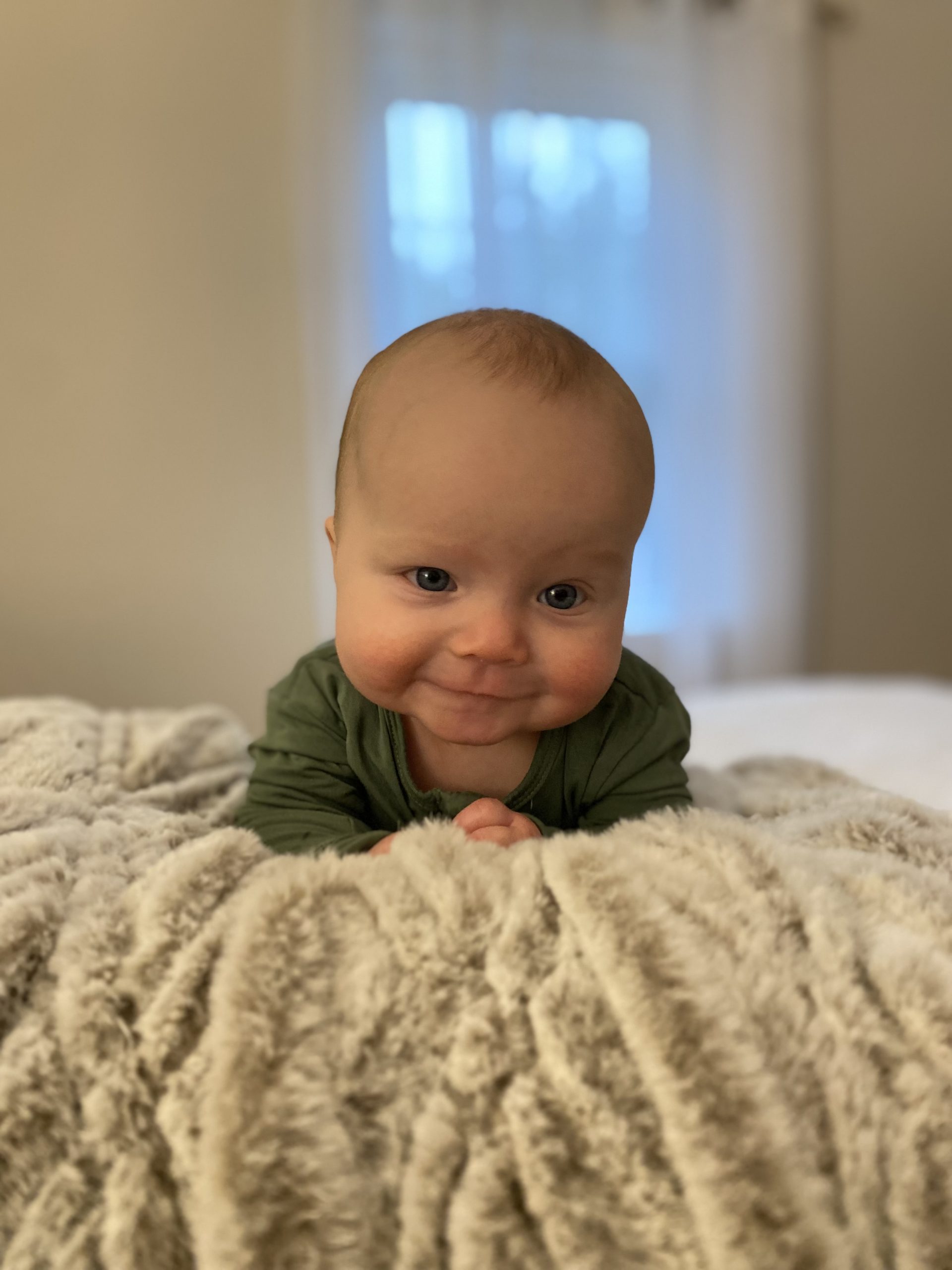 Infant lifting head up and smiling during tummy time